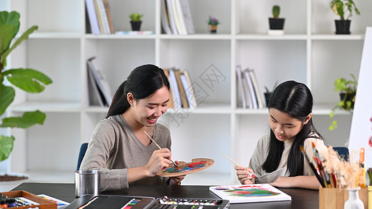 快乐的亚洲年轻母亲和女儿一起在家里画画图片