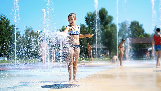 快乐的八岁穿泳衣的女孩在街头城市喷泉 户外 公园 夏日 阳光炎热的假期中玩得开心女性活动假期闲暇娱乐享受行动家庭太阳孩子图片