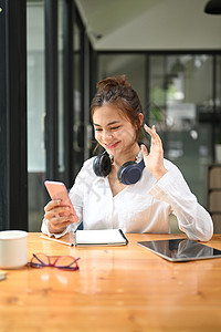 快乐的年轻女子挥手 在网上聊天 用手机进行视频电话游戏图片