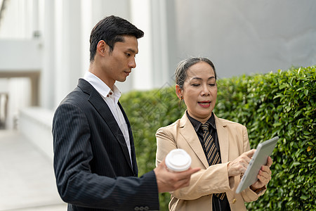 成功的亚洲商务人士和年老商业女商务人士与大楼外的平板商谈成功进行中幸福团队团体伙伴男人商务工作工人讨论通讯图片