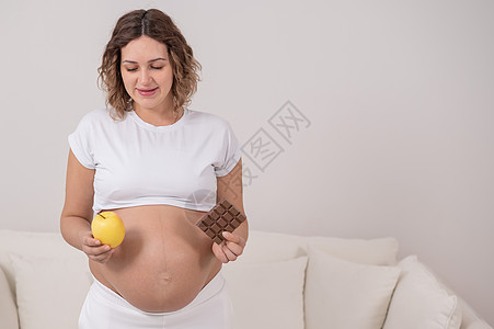 怀孕妇女持有苹果和巧克力 怀孕九个月就已经是第九个月了母性分娩酒吧婴儿营养孩子腹部父母女孩甜点图片