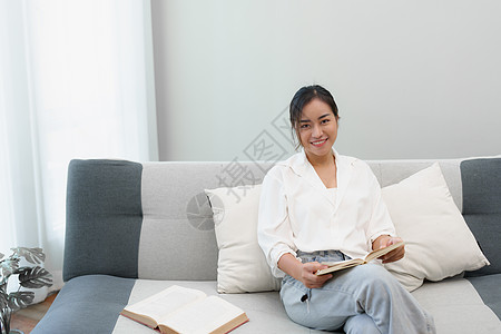 一个坐在沙发上的女人的Hobby 正在读一本书来放松短袜学生情感房子享受窗户青少年客厅快乐文学图片