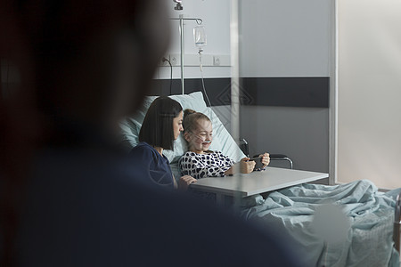 母亲在看卡通时 坐在住院女儿旁边接受治疗的医院女儿旁图片