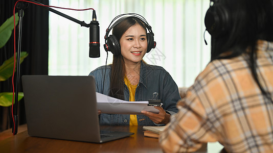 在家中演播室的电台访谈访客谈话中 带着耳机微笑的无线电主持人和录音声音图片