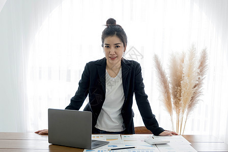 迷人的亚洲女商务人士 带着微笑站在办公室里 聪明地看着摄影机 看着摄像头图片
