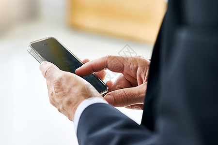 搜索广大的虚拟世界 一个公司商务人士在办公室手机上发短信的近拍片子 你看到了吗?图片