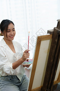 一个亚洲女人在闲暇时间设计艺术的肖像摄影成人快乐技术材料青少年老师画家画笔电脑图片