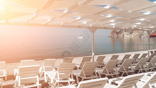 海滩上的天篷下空荡荡的躺椅 海滩区是空的 没有人 遮阳罩下的白色塑料日光浴床 假期结束 假期开始 等待游客蓝色海洋帐篷甲板闲暇旅图片