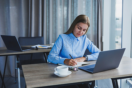 秘书检查时间表 戴着眼镜 面带微笑 开朗的年轻美女坐在工作场所时使用笔记本电脑经理职场女性商务工作桌子互联网快乐企业家技术图片