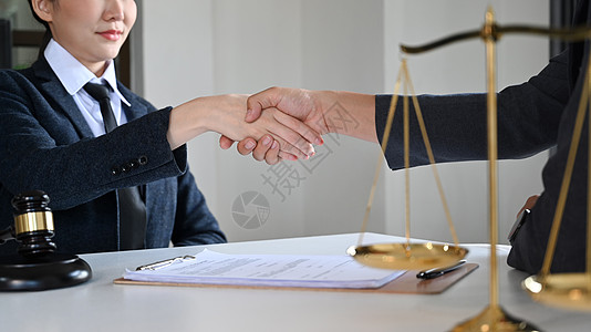 执法法官自信的女律师或律师在合同协议后与客户握手的剪影背景