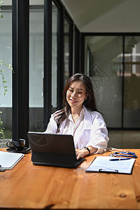 穿着白制服的微笑女医生 分析病人诊断或医院报告情况 (b) 在医院里对检查结果进行分析图片