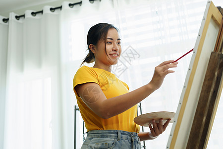 一个亚洲女人在闲暇时间设计艺术的肖像青少年课堂快乐抽屉服装电脑材料画家成人画笔图片