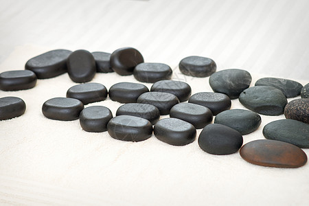 许多黑色按摩石落在桌子上的毛巾上 被孤立竹子疗法芳香卵石生活卫生石头药品沙龙保健图片
