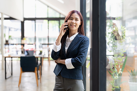 亚洲女性站着打电话 和客户交谈 微笑 笑声办公室商业电脑工作手机职场女士笔记本企业家成人图片