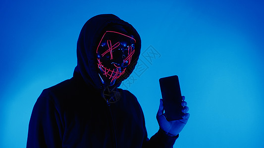 数字安全概念 隐形黑客戴着智能手机面具的匿名黑客手指电脑隐私互联网屏幕技术个人数据商务检测图片