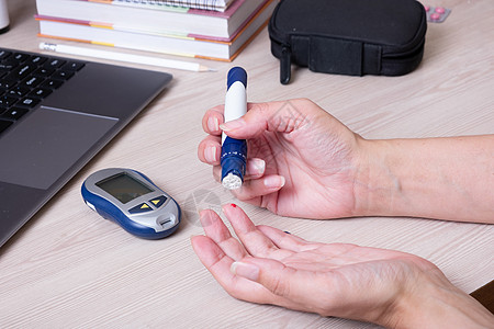 桌子上有血糖仪的女性手 糖尿病患者的生活方式 测量葡萄糖水平药品仪表诊断胰岛素保健卫生监视器电子疾病手指图片