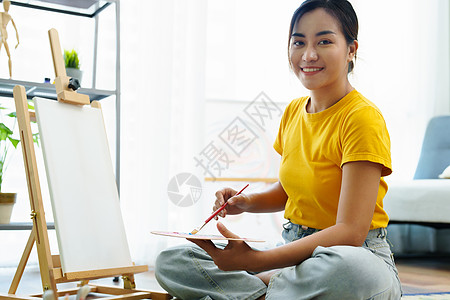 一个亚洲女人在闲暇时间设计艺术的肖像画笔学生画架青少年快乐作坊服装老师摄影课堂图片