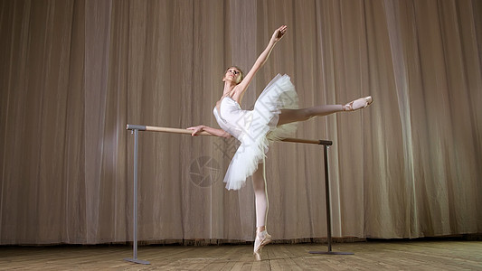 芭蕾排练 在旧剧院大厅 身穿白色芭蕾舞裙的年轻芭蕾舞女演员 芭蕾舞短裙 正在芭蕾舞中 优雅地表演某种芭蕾舞练习 态度 allon图片