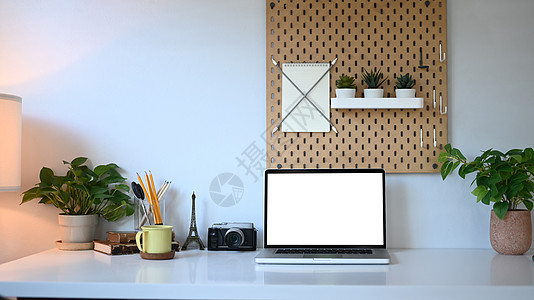 用空屏幕 咖啡杯 家用植物和家庭办公室白桌上用品的膝上型计算机前视镜图片