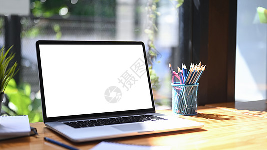 特写电脑笔记本电脑 在木制桌子上用空屏幕和铅笔架图片