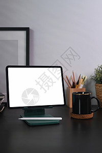 数字平板电脑 咖啡杯和黑木桌上的铅笔持有者图片