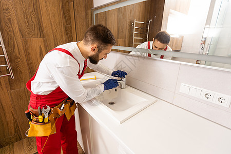 工人在浴室安装洗手盆家具成人房子修理工职业推杆男人盆地工作龙头图片
