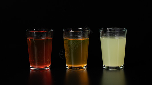 黑色背景的三杯彩色水 饮料 果汁和鸡尾酒图片