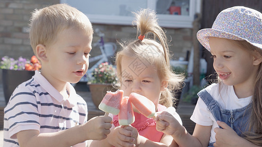 三个可爱的小孩享用美味的冰淇淋甜筒 孩子吃西瓜冰棒 家庭花园里的孩子们的兄弟姐妹零食糖果 暑假炎热的天气晴天 童年 食品糖果青年图片