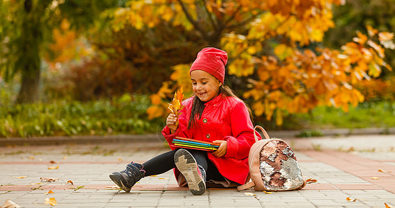 小学学生手头拿着书 在户外建筑附近有背包的女孩 开始上课 第一天秋天 笑声小学生女学生时间时尚女性童年街道学校孩子书包图片
