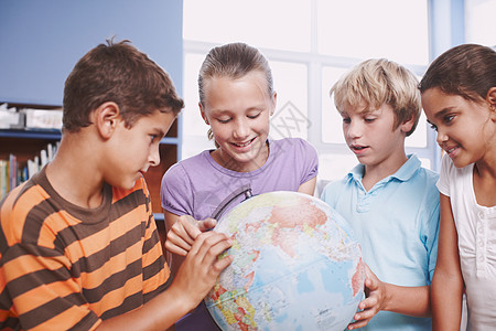 了解世界上不同的国家 一群小学生使用地球仪了解世界高清图片