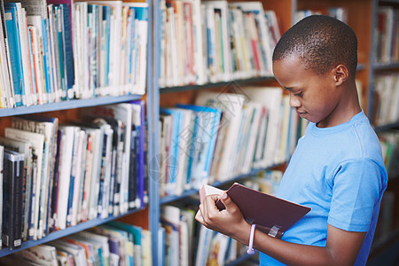 图书馆是激发创意的好地方 一个非洲裔美国男孩在图书馆看一本好书图片