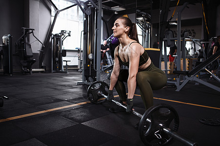 体育馆的年轻健身运动员健身房杠铃硬拉身体举重运动健康动机训练女士图片