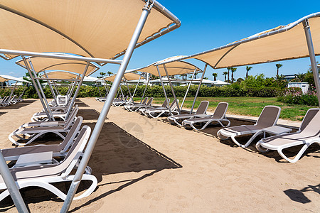 在土耳其度假胜地荒沙沙滩上排成一排防晒床 在旅馆等候游客的太阳休息者蓝色椅子阳伞海洋假期躺椅遮阳棚天堂旅行天空图片