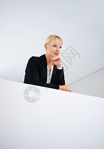 商业妇女思考 思想深刻的商业妇女站在墙边靠着下巴站着图片