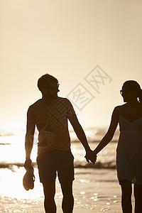 一对情侣手牵手 在海面上朝太阳游荡 (笑声)图片