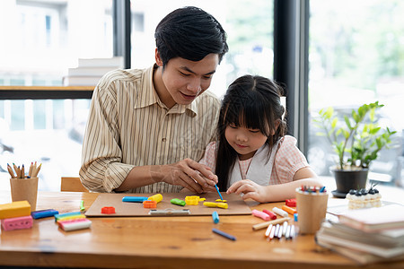 年幼的亚洲父亲和女儿在桌子上一起用塑胶或玩钱图片