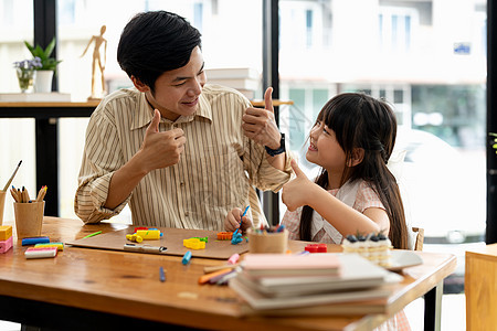 骄傲的亚裔父亲和女儿可塑胶或者在桌子上玩钱图片