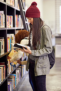 打开一本书 你就会敞开心扉 一位站在图书馆书架旁读书的年轻女子图片