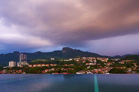 傍晚的雨云为绿山下城市带来雨水图片