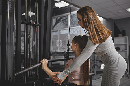 在体育馆与个人教练员一起运动的少女下拉纬度职业女士身体培训师青少年女孩教练肌肉图片