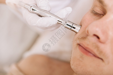 年轻人接受美容师的面部皮肤护理治疗客户医生温泉程序去角质沙龙皮肤科诊所服务皱纹图片