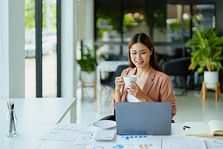 一个女人在使用电脑时休息喝咖啡的肖像水平咖啡商务摄影棕色情感办公室商业生意咖啡杯图片