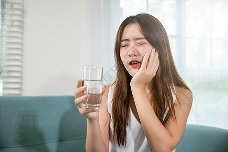 美丽的女性牙痛和牙齿问题 在喝冷水后触到脸颊疼痛的感觉;图片