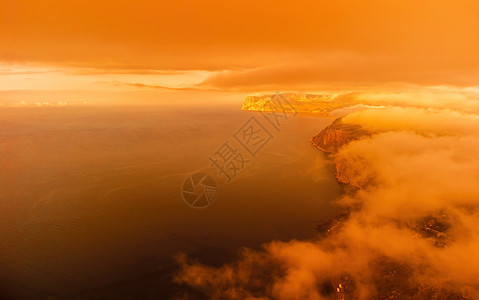 海上的红色燃烧日落与岩石火山悬崖 抽象自然夏季或春季海洋背景 金色温暖水面上的小波浪与来自太阳的散景灯调子天空海滩温泉运动辉光火图片
