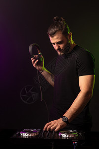 DJ 以多彩雾背景在混音器播放音乐男性房子庆典光盘控制耳机乐趣紫色舞蹈夜店图片