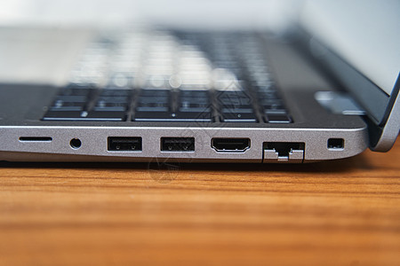 木制桌上灰色笔记本电脑键盘的侧边视图 USB 移植在笔记本电脑上图片