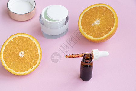 粉红色背景上的面部血清 奶油和橙色 维生素 c 概念图片