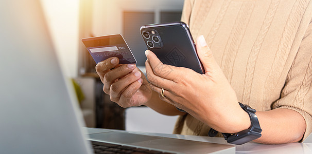 在家购买产品的女性手持信用卡和智能手机信用电子命令电话商业银行业网络店铺借方笔记本图片
