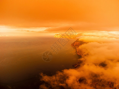 海上的红色燃烧日落与岩石火山悬崖 抽象自然夏季或春季海洋背景 金色温暖水面上的小波浪与来自太阳的散景灯蓝色海滩火花水池季节阳光晴图片