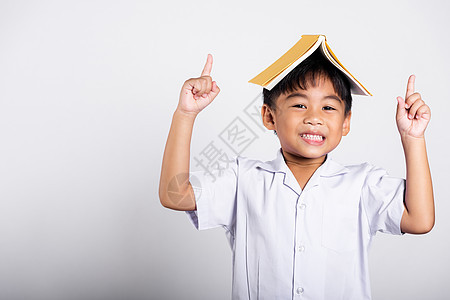 亚洲可爱的蹒跚学步的孩子笑得开心 穿着泰国学生制服的红裤子站着 像屋顶一样把书举过头顶红色情感学习学校头发乐趣快乐微笑青春期工作图片